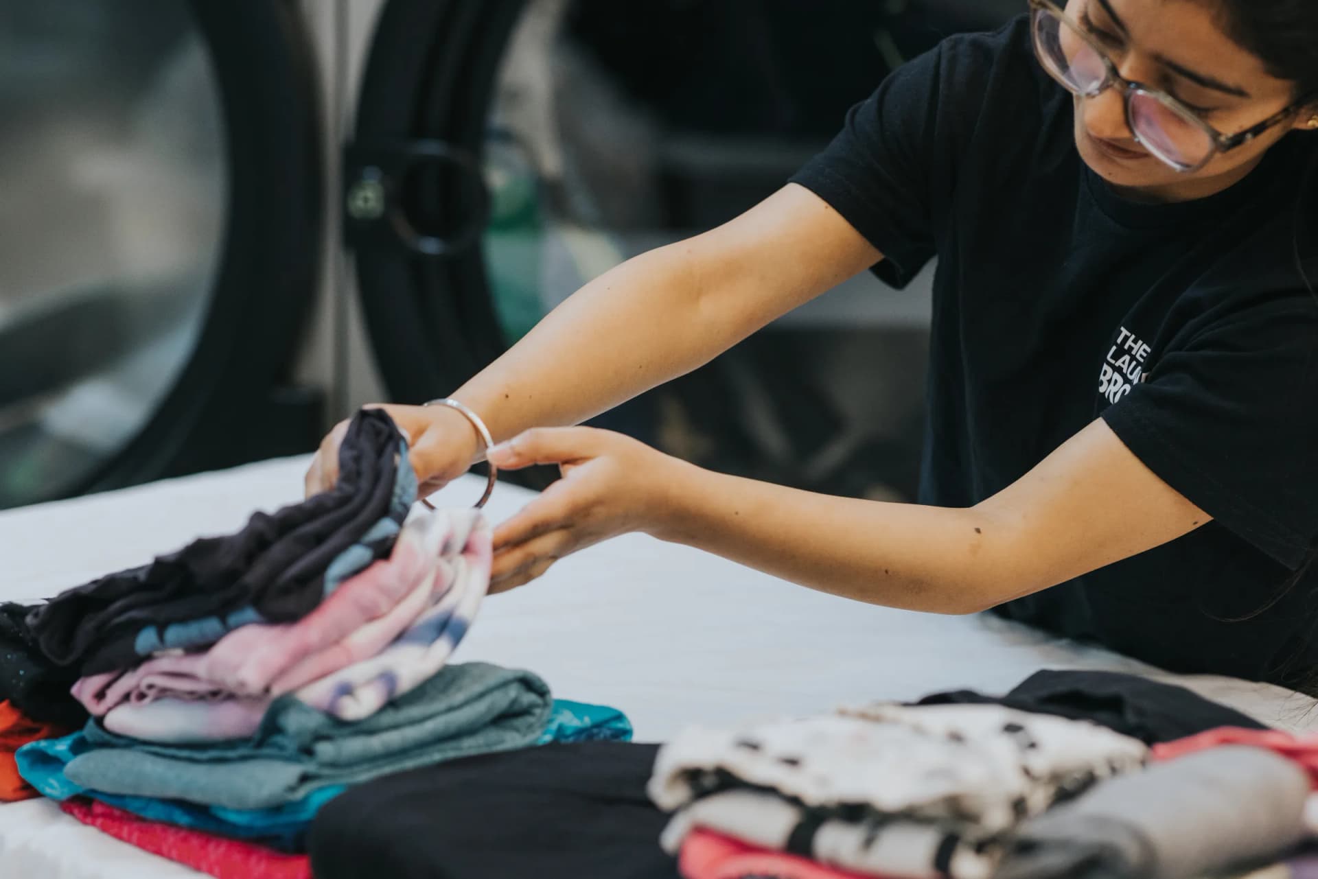 Staff member folding clean laundry with care at the facility.