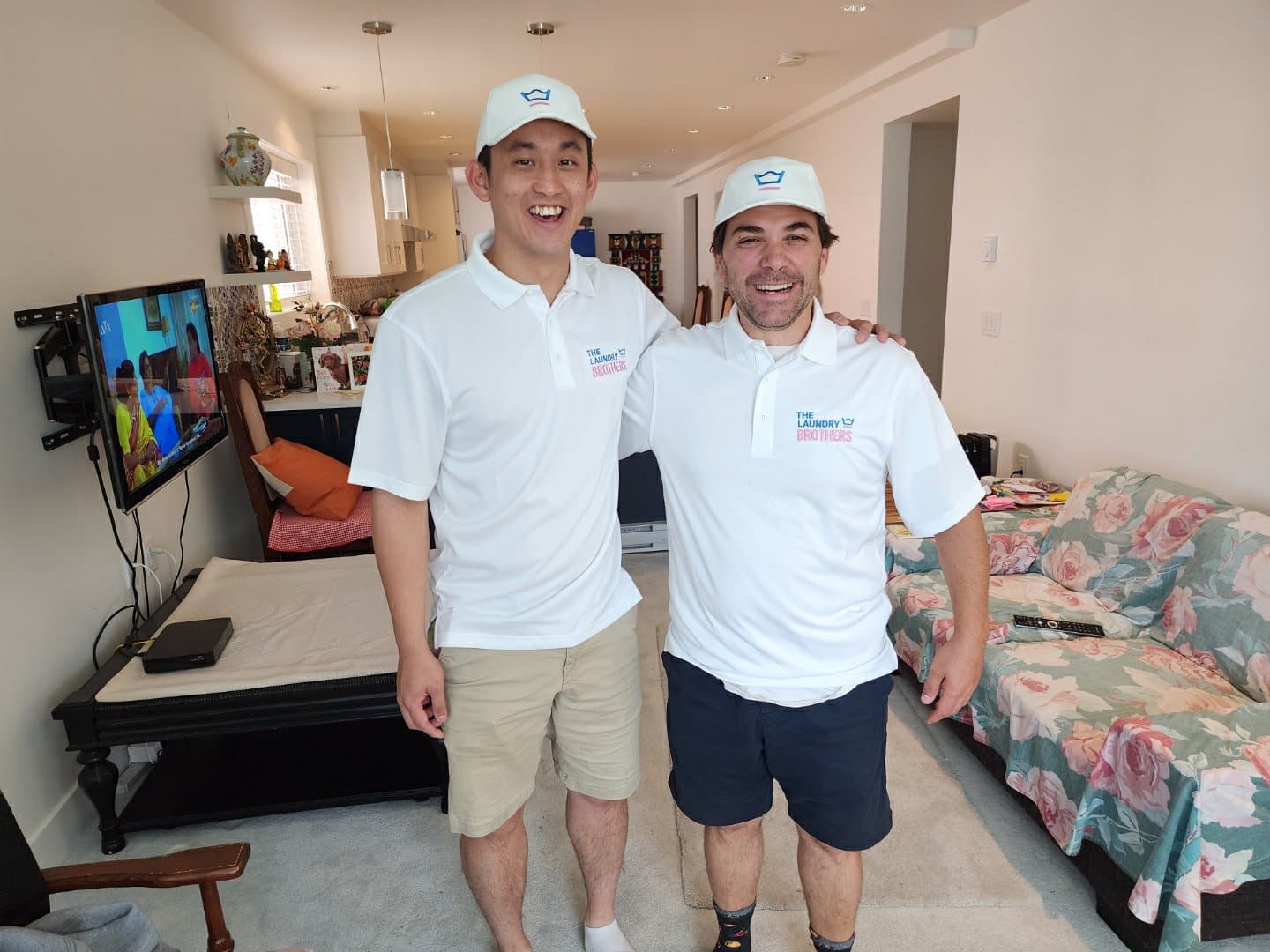 The two founders of The Laundry Brothers, wearing branded polo shirts and caps, smiling together.