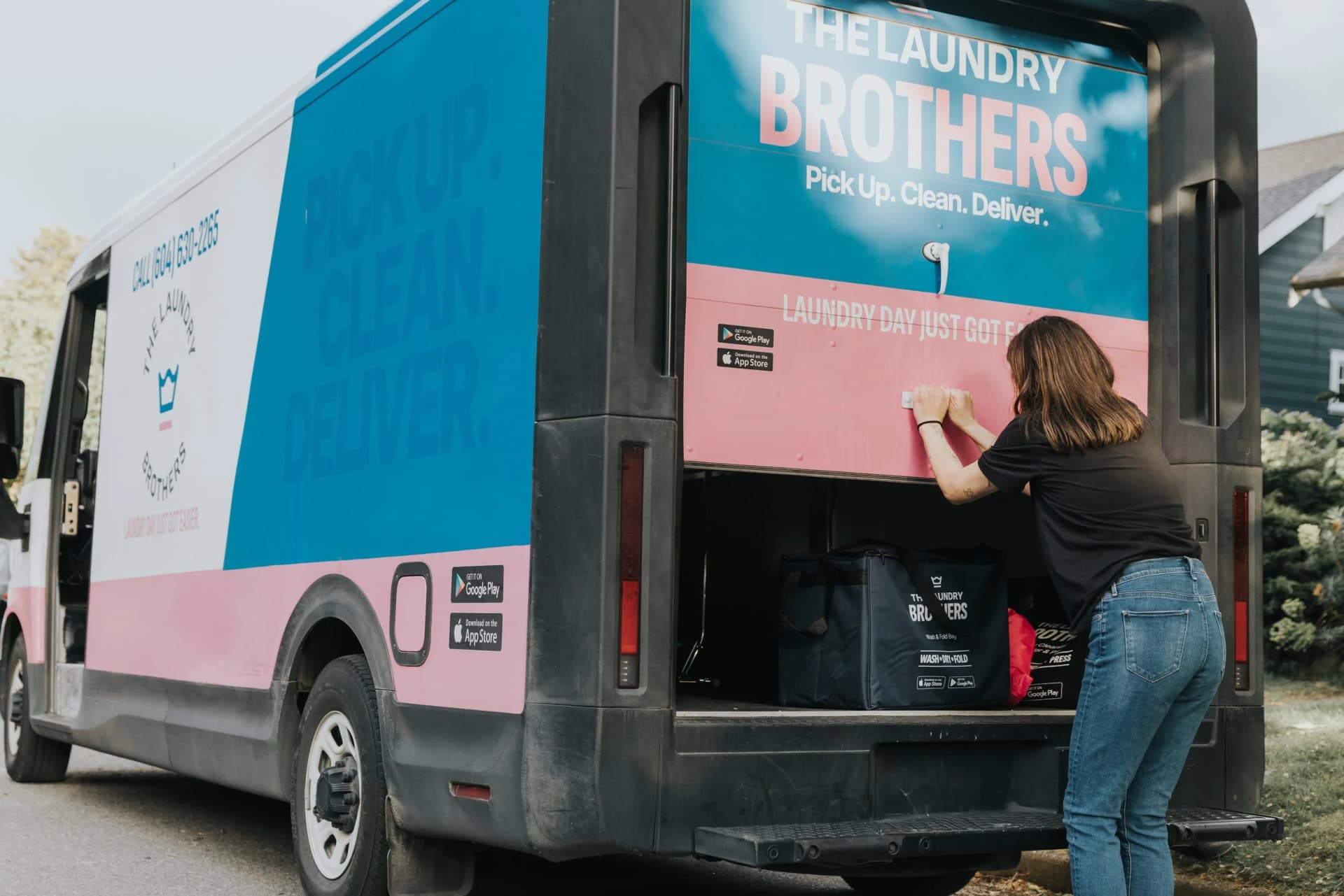 A Laundry Brothers driver handing over a fresh laundry delivery at a customer's front door.