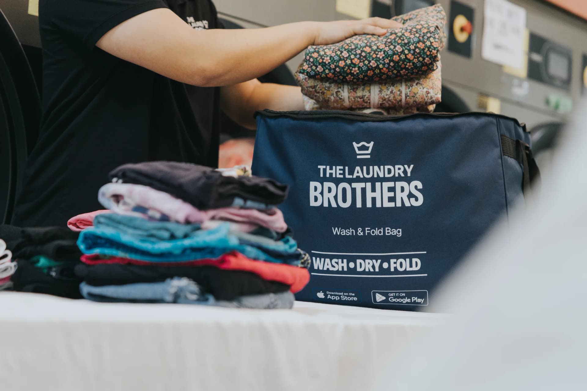 A Laundry Brothers staff member loading the branded wash & fold bag with sorted laundry at the facility.